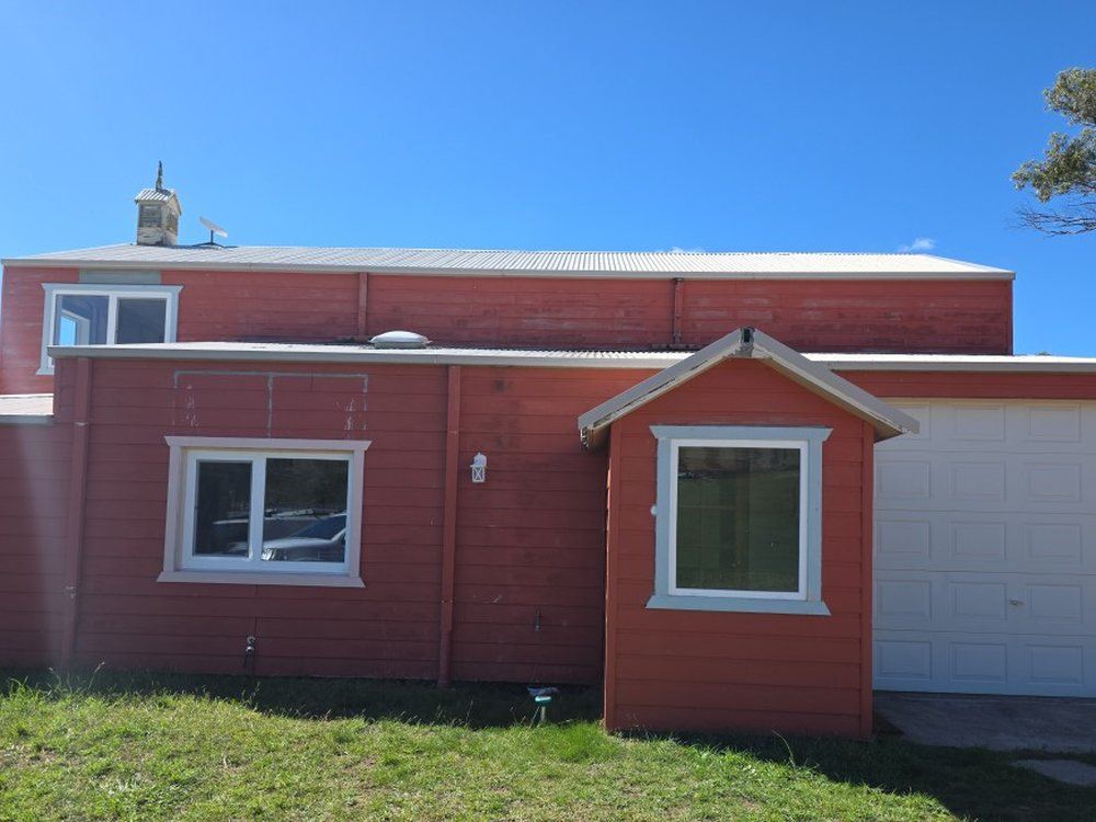 Red weatherboard exterior mid-repaint